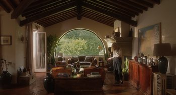 Movie still from “Book Club: The Next Chapter” (2023), directed by Bill Holderman – A woman standing in front of a fireplace in a living room; Extreme Wide shot, High angle