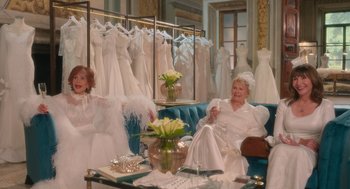 Movie still from “Book Club: The Next Chapter” (2023), directed by Bill Holderman – Two women sitting on a couch in front of dresses; Wide shot, Over the shoulder angle