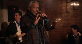 Movie still from “Book Club: The Next Chapter” (2023), directed by Bill Holderman – An older black man singing into a microphone; Medium shot, Low angle