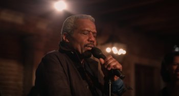 Movie still from “Book Club: The Next Chapter” (2023), directed by Bill Holderman – An older man is holding a microphone and singing; Close Up shot, Low angle