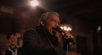 Movie still from “Book Club: The Next Chapter” (2023), directed by Bill Holderman – A man with a beard is singing into a microphone; Close Up shot, Low angle