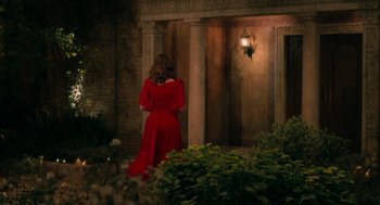 Movie still from “Book Club: The Next Chapter” (2023), directed by Bill Holderman – A woman in a red dress standing in front of a building; Wide shot, Over the shoulder angle