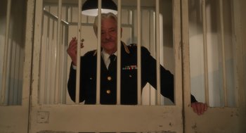 Movie still from “Book Club: The Next Chapter” (2023), directed by Bill Holderman – An old man in a military uniform behind bars in a jail cell; Medium shot, Low angle