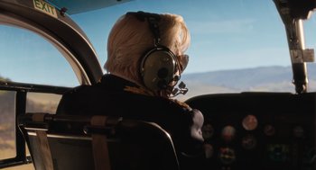 Movie still from “Book Club: The Next Chapter” (2023), directed by Bill Holderman – A person wearing headphones sitting in the cockpit of an airplane; Medium shot, Over the shoulder angle