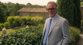 Movie still from “Book Club: The Next Chapter” (2023), directed by Bill Holderman – An older man wearing a suit and tie standing in front of bushes; Medium shot, Over the shoulder angle