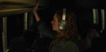Movie still from “Books of Blood” (2020), directed by Brannon Braga – A woman wearing headphones is standing in a dark room; Close Up shot, Over the shoulder angle
