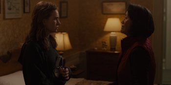 Movie still from “Books of Blood” (2020), directed by Brannon Braga – Two women are talking in a dimly - lit room; Medium shot, Over the shoulder angle