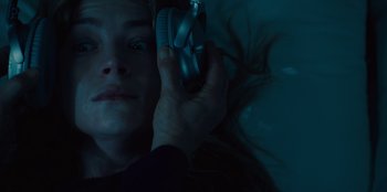 Movie still from “Books of Blood” (2020), directed by Brannon Braga – A woman laying in a bed holding a pair of headphones; Close Up shot, Overhead angle