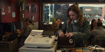 Movie still from “Books of Blood” (2020), directed by Brannon Braga – A woman is holding a purse while standing in front of a printer; Medium shot, Over the shoulder angle
