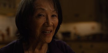 Movie still from “Books of Blood” (2020), directed by Brannon Braga – An older asian woman smiling at the camera; Extreme Close Up shot, Over the shoulder angle