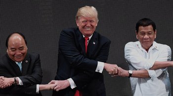 Movie still from “Borat Subsequent Moviefilm” (2020), directed by Jason Woliner – A man in a black suit and a red tie shaking hands; Medium shot, Over the shoulder angle