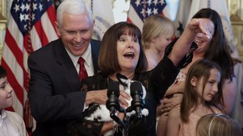 Movie still from “Borat Subsequent Moviefilm” (2020), directed by Jason Woliner – A man and a woman holding a cat in the air; Close Up shot, Over the shoulder angle