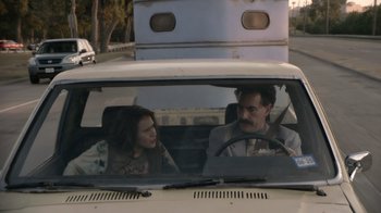 Movie still from “Borat Subsequent Moviefilm” (2020), directed by Jason Woliner – A man and a woman sitting in the back of a car; Medium shot, Over the shoulder angle