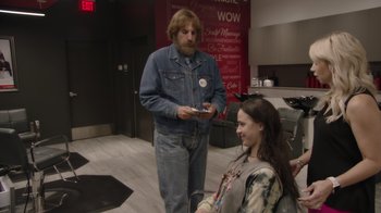 Movie still from “Borat Subsequent Moviefilm” (2020), directed by Jason Woliner – A man standing next to a woman in front of a red wall; Medium shot, Over the shoulder angle