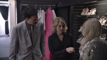 Movie still from “Borat Subsequent Moviefilm” (2020), directed by Jason Woliner – A man and a woman in a suit and tie looking at dresses; Medium shot, Over the shoulder angle