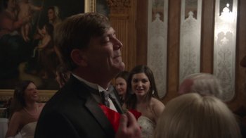 Movie still from “Borat Subsequent Moviefilm” (2020), directed by Jason Woliner – A man in a tuxedo holding a flower in his mouth; Close Up shot, Over the shoulder angle