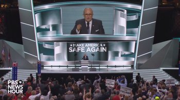 Movie still from “Borat Subsequent Moviefilm” (2020), directed by Jason Woliner – A large group of people gathered in front of a large screen; Extreme Wide shot, Low angle