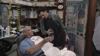 Movie still from “Borat Subsequent Moviefilm” (2020), directed by Jason Woliner – A barber showing a man a haircut in a barber shop; Wide shot, Over the shoulder angle