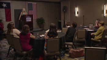 Movie still from “Borat Subsequent Moviefilm” (2020), directed by Jason Woliner – A group of people sitting around a table; Wide shot, Low angle