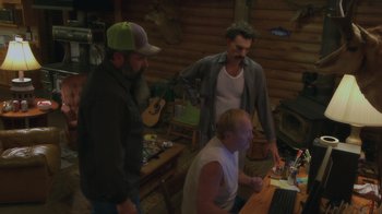 Movie still from “Borat Subsequent Moviefilm” (2020), directed by Jason Woliner – A group of men standing around a laptop computer; Wide shot, High angle