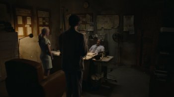 Movie still from “Borat Subsequent Moviefilm” (2020), directed by Jason Woliner – A group of people standing around a table; Wide shot, Over the shoulder angle