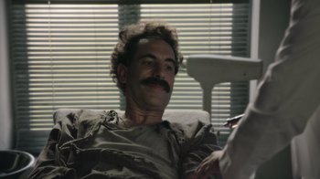 Movie still from “Borat Subsequent Moviefilm” (2020), directed by Jason Woliner – A man with a mustache is sitting in a chair; Close Up shot, High angle