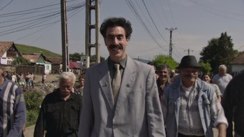Movie still from “Borat Subsequent Moviefilm” (2020), directed by Jason Woliner – A group of people walking down a street; Wide shot, Low angle
