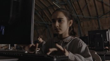 Movie still from “Borat Subsequent Moviefilm” (2020), directed by Jason Woliner – A young girl using a computer in a room; Close Up shot, High angle