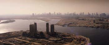 Movie still from “Born a Champion” (2021), directed by Alex Ranarivelo – An aerial view of a city with a large body of water in front of it; Extreme Wide shot, High angle