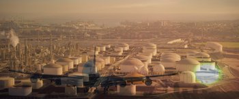 Movie still from “Born a Champion” (2021), directed by Alex Ranarivelo – An airplane flying over a large oil refinery; Extreme Wide shot, High angle