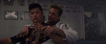 Movie still from “Born a Champion” (2021), directed by Alex Ranarivelo – A man and a young boy sitting next to each other; Close Up shot, Over the shoulder angle