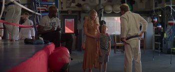 Movie still from “Born a Champion” (2021), directed by Alex Ranarivelo – A woman and a boy standing next to each other in a room; Wide shot, Over the shoulder angle
