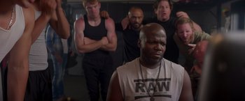 Movie still from “Born a Champion” (2021), directed by Alex Ranarivelo – A group of men standing next to each other in a room; Medium shot, Over the shoulder angle