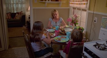 Movie still from “Boyhood” (2014), directed by Richard Linklater – A woman sitting at a dinner table with two children; Medium shot, High angle