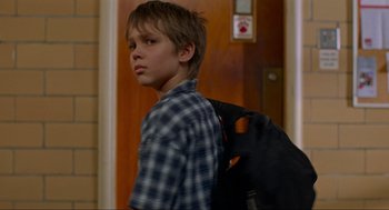 Movie still from “Boyhood” (2014), directed by Richard Linklater – A young boy with a backpack standing next to a door; Close Up shot, Over the shoulder angle