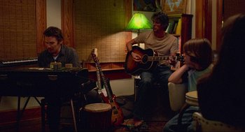 Movie still from “Boyhood” (2014), directed by Richard Linklater – A group of people sitting in a living room playing instruments; Wide shot, Over the shoulder angle