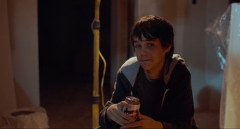 Movie still from “Boyhood” (2014), directed by Richard Linklater – A young man sitting on the side of the road holding a can of soda; Medium shot, Over the shoulder angle