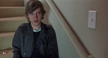 Movie still from “Boyhood” (2014), directed by Richard Linklater – A young man sitting in a corner wearing a black jacket; Close Up shot, Over the shoulder angle