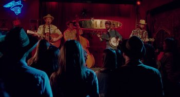 Movie still from “Boyhood” (2014), directed by Richard Linklater – A group of men playing instruments in front of an audience; Wide shot, Over the shoulder angle