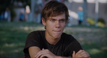 Movie still from “Boyhood” (2014), directed by Richard Linklater – A young man sitting on the grass with his hands crossed; Close Up shot, Over the shoulder angle