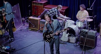 Movie still from “Boyhood” (2014), directed by Richard Linklater – A man holding a microphone and holding a guitar; Wide shot, Overhead angle