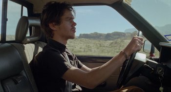 Movie still from “Boyhood” (2014), directed by Richard Linklater – A man driving a car in the middle of the desert; Close Up shot, Low angle