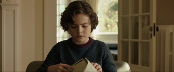 Movie still from “Brahms: The Boy II” (2020), directed by William Brent Bell – A young boy is holding a notebook in his hands; Close Up shot, Over the shoulder angle