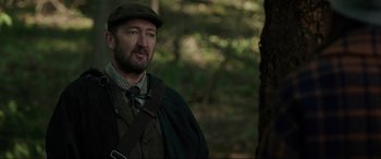 Movie still from “Brahms: The Boy II” (2020), directed by William Brent Bell – A person wearing a hat near a tree; Close Up shot, Over the shoulder angle