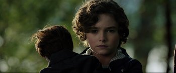 Movie still from “Brahms: The Boy II” (2020), directed by William Brent Bell – A young man with a curly hair and a brown jacket; Close Up shot, Over the shoulder angle