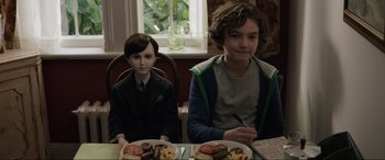 Movie still from “Brahms: The Boy II” (2020), directed by William Brent Bell – Two boys sitting at a table with plates of food on it; Medium shot, High angle