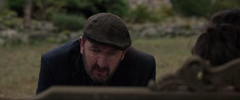 Movie still from “Brahms: The Boy II” (2020), directed by William Brent Bell – A man wearing a hat looking down at something; Close Up shot, Over the shoulder angle