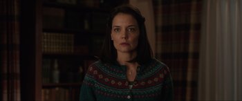 Movie still from “Brahms: The Boy II” (2020), directed by William Brent Bell – A woman in a green sweater standing in front of a book shelf; Close Up shot, Over the shoulder angle