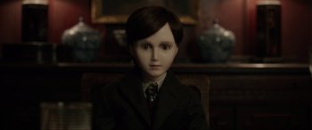 Movie still from “Brahms: The Boy II” (2020), directed by William Brent Bell – A boy wearing a suit and tie sitting in a chair; Close Up shot, High angle