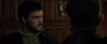 Movie still from “Brahms: The Boy II” (2020), directed by William Brent Bell – A man with a goatee talking to another man in front of a door; Close Up shot, Over the shoulder angle